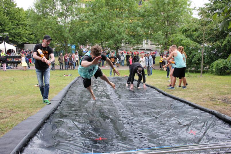 Studierende bei einem Spaßwettbewerb springen über eine schwarze Folie.
