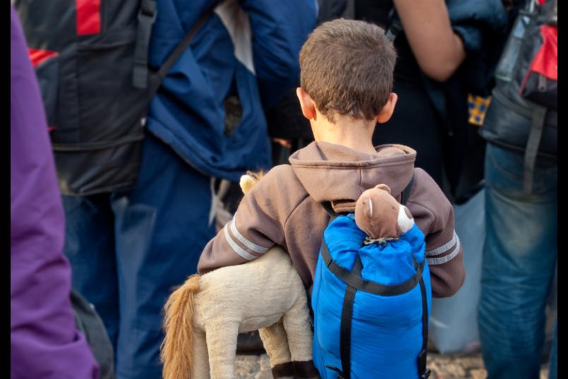 Kleiner Junge von hinten mit Stofftier in Menschenmasse
