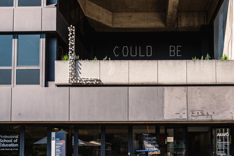 Schriftzug "L COULD BE" aus Glühbirnen an einem Gebäude