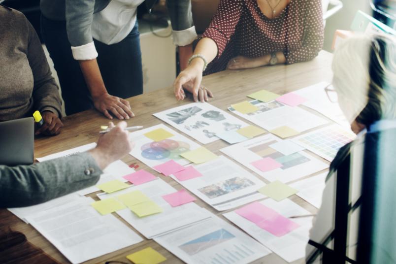 Arbeitssituation mit Papieren und Post-its an einem großen Tisch
