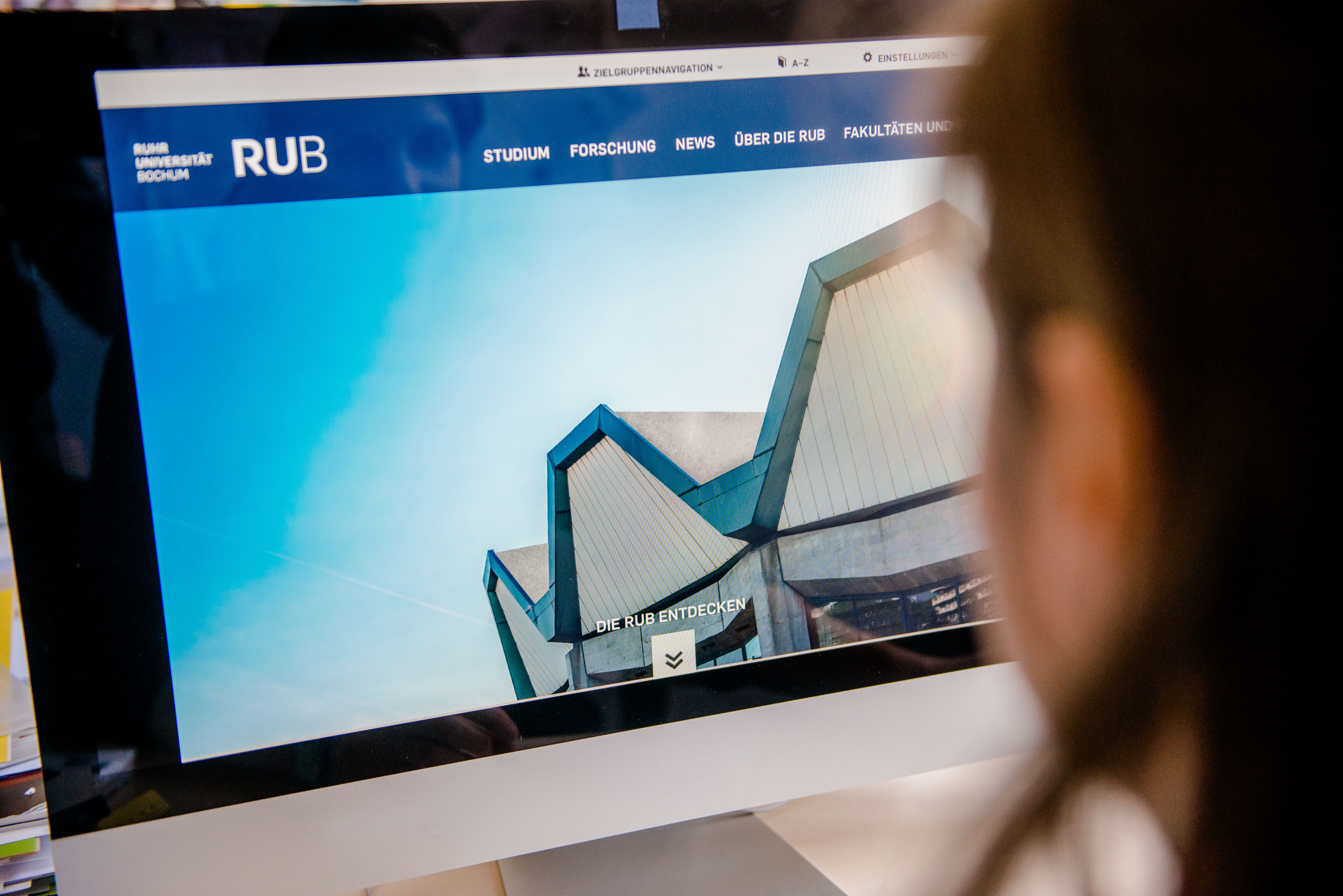 Frau am Computerbildschirm sieht das neue Webdesign der RUB