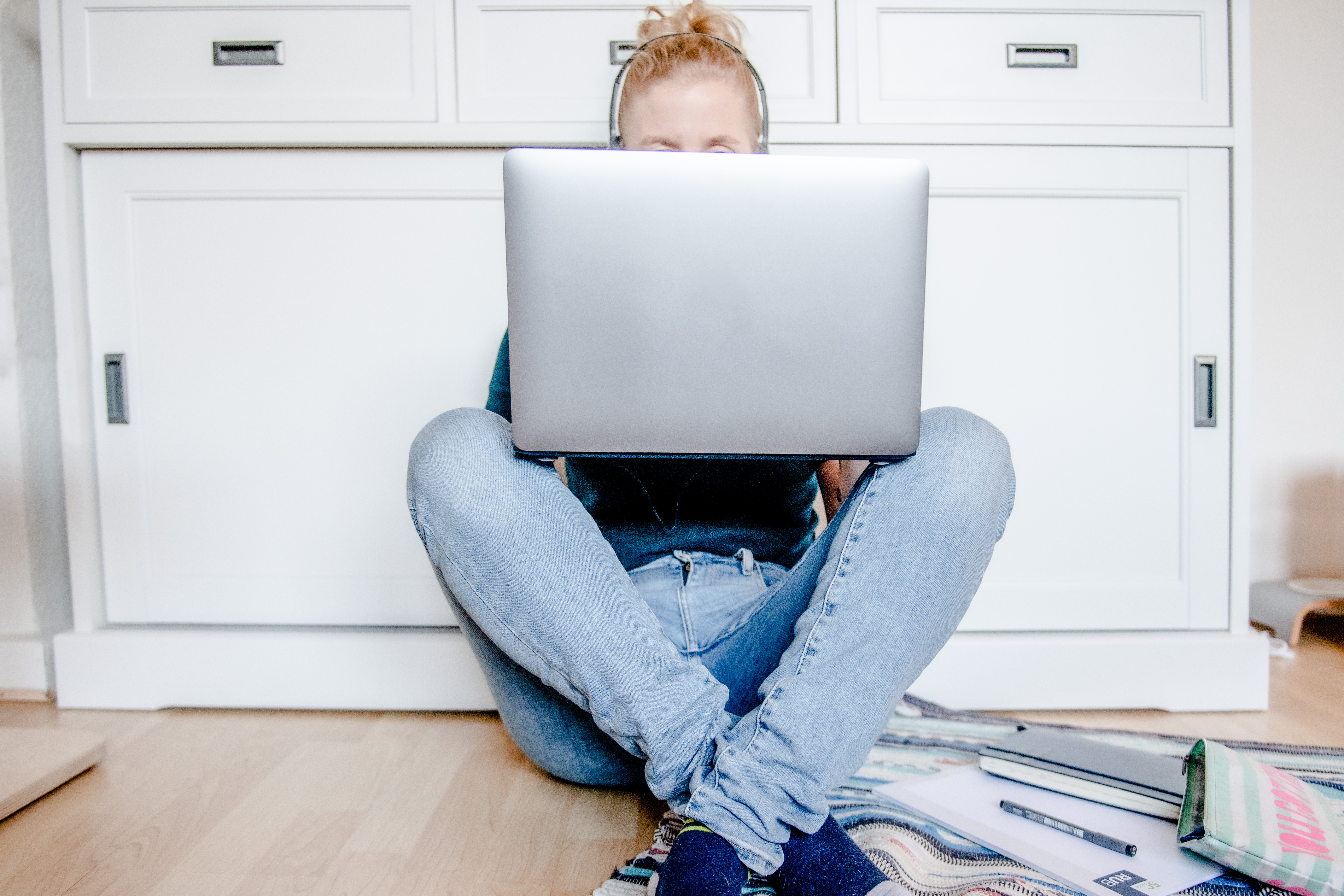 Studentin sitzt mit Laptop auf dem Boden. 