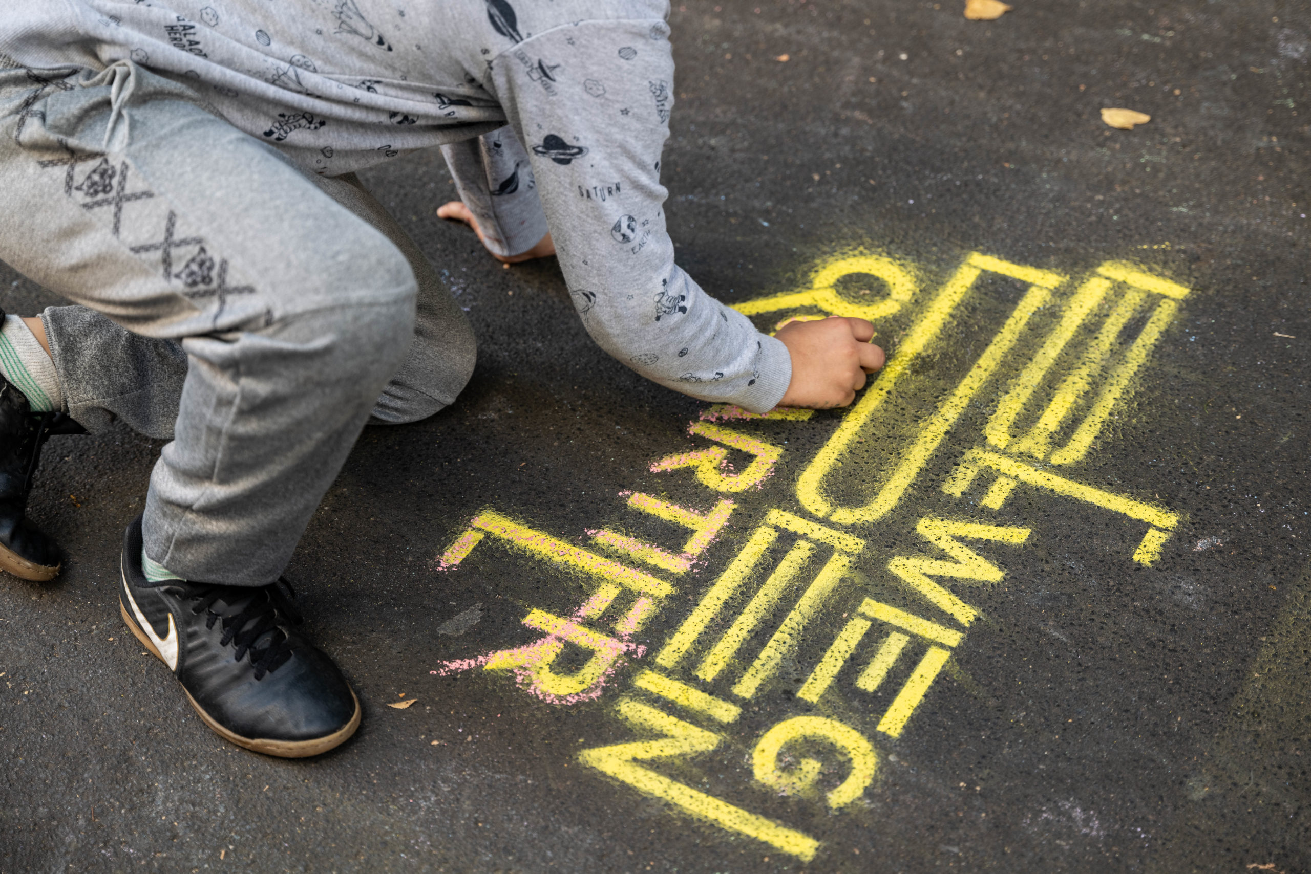 Eine Person sprüht das Logo des Projekts "Beweg dein Quartier" auf den Boden.