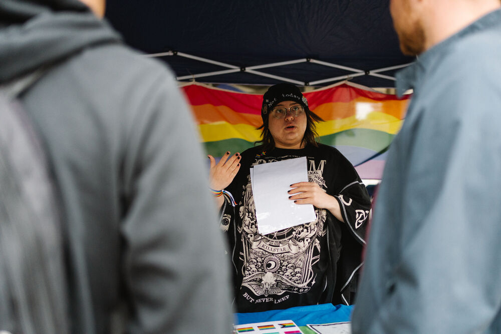 Menschen im Gespräch im Hintergrund eine Regenbogenflagge