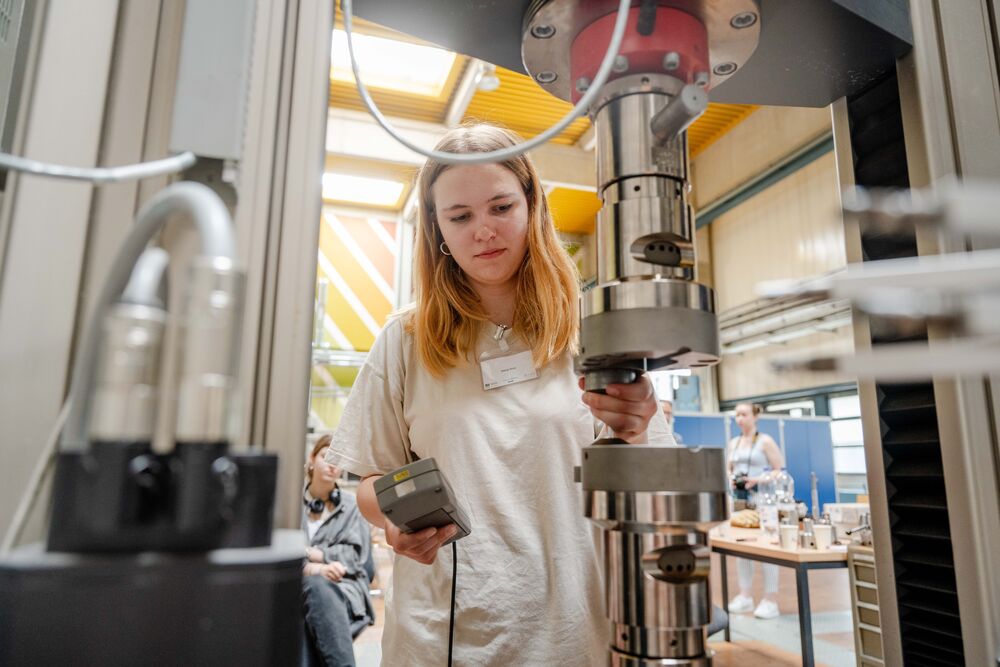 Eine Person setzt eine Metallprobe in einen Versuchsstand ein.