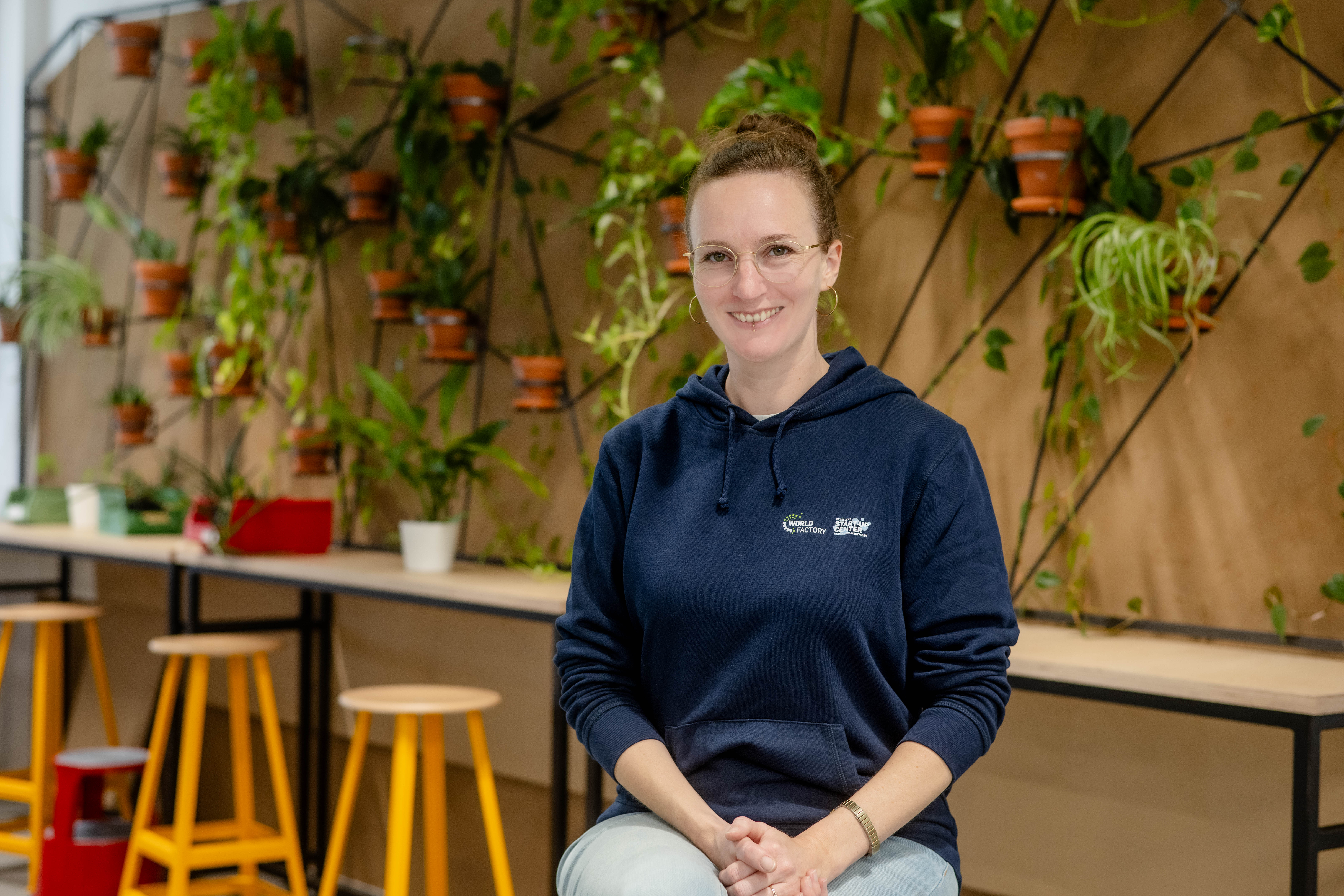 Gründungsberaterin Melusine Reimers vor einer Wand mit Pflanzen im Makerspace.