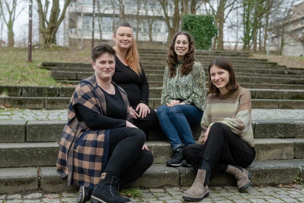 Frauen sitzen nebeneinander auf einer Treppe. 