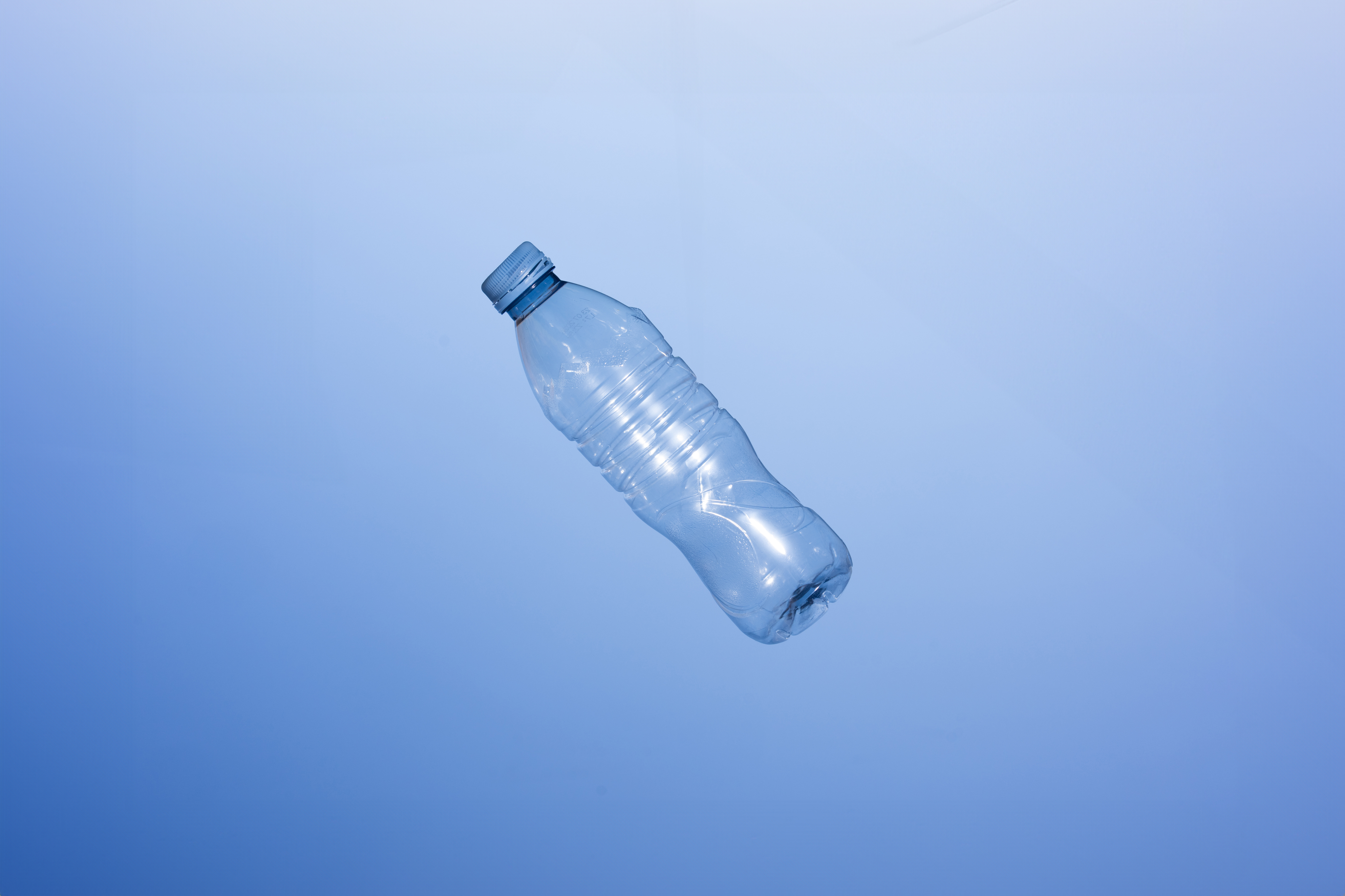 Eine leere PET-Flasche vor einem blauen Hintergrund