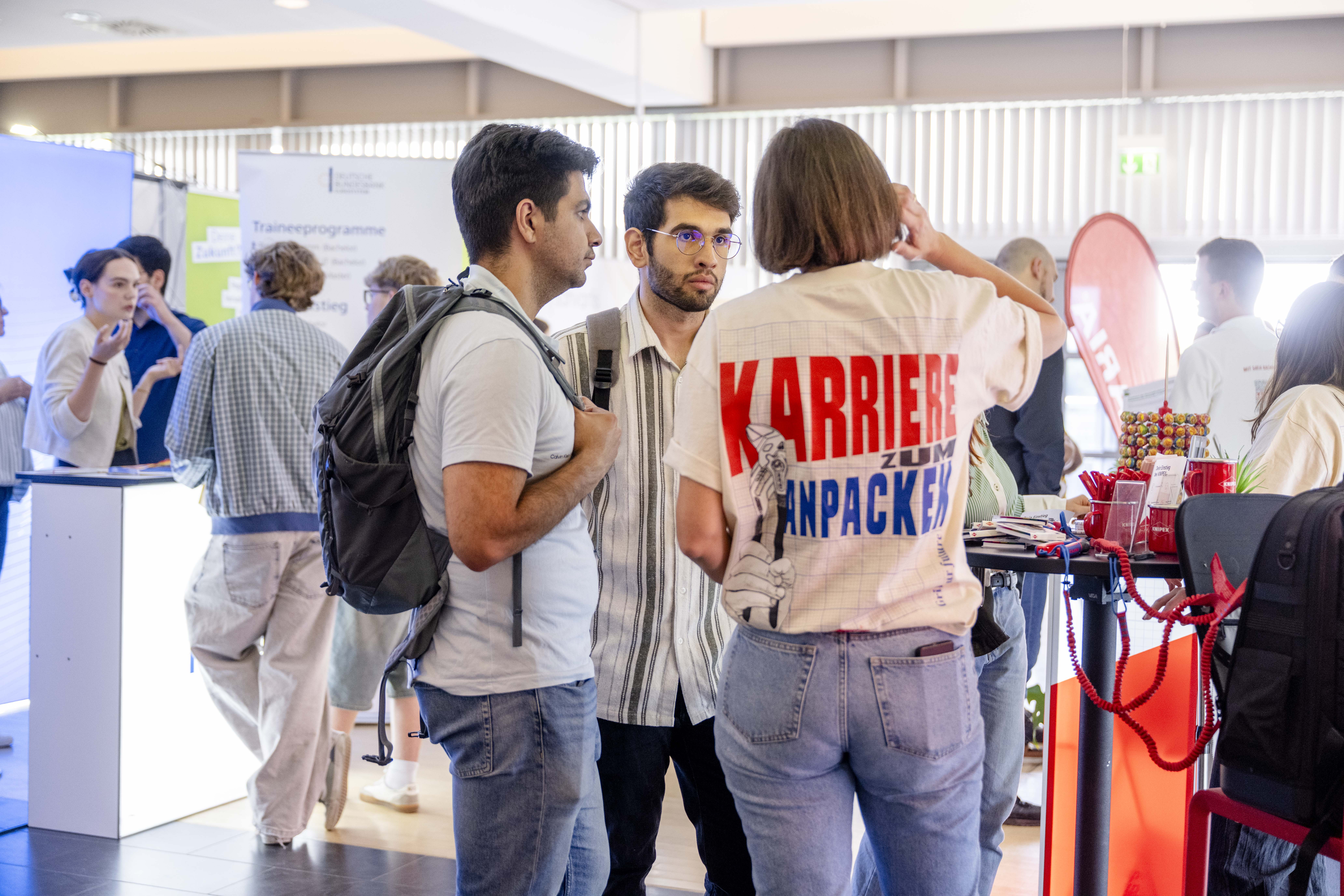 Zwei junge Männer lassen sich auf einer Messe beraten. 