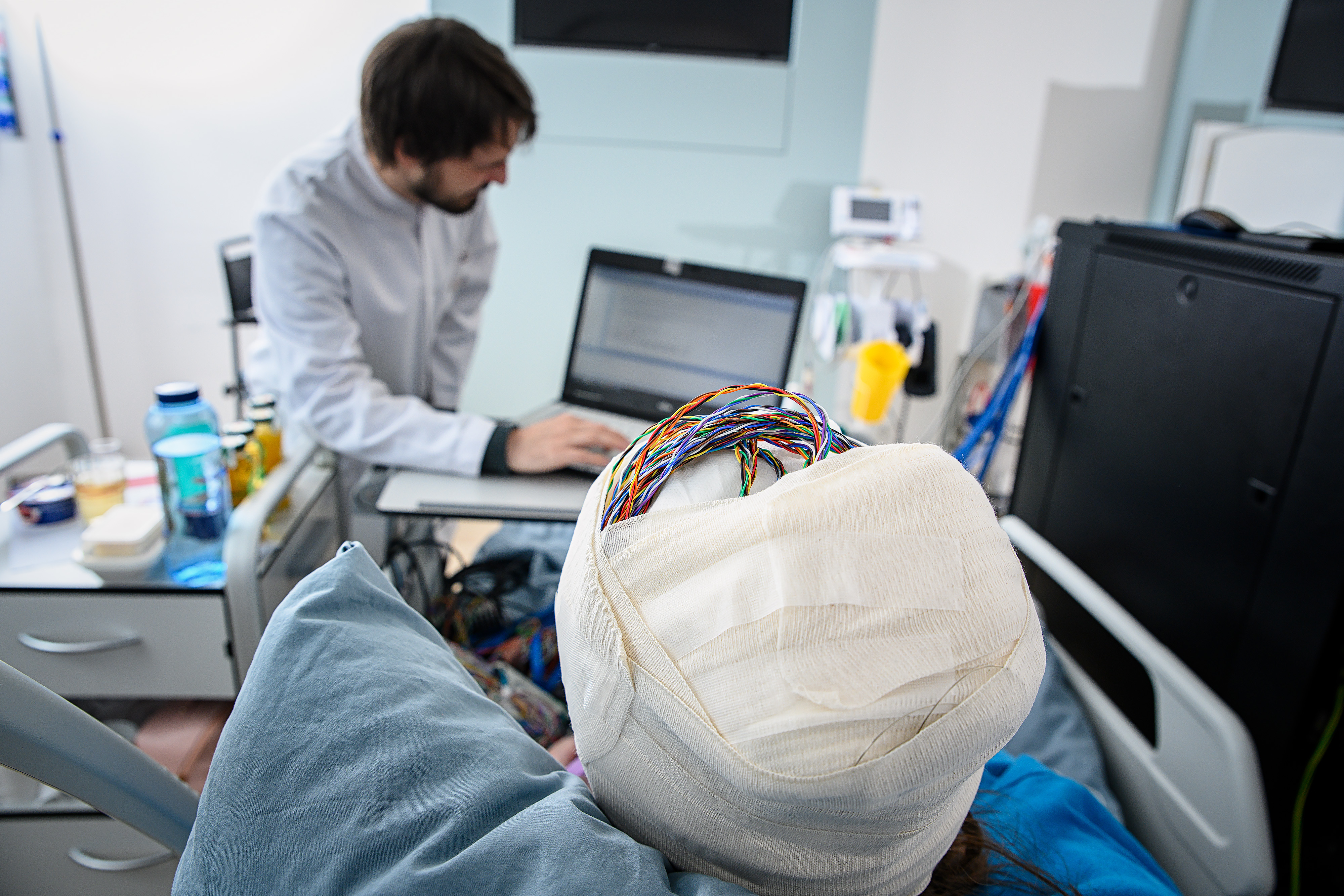 Eine Person mit verbundenem Kopf, aus dem Verband schauen Kabel heraus. 