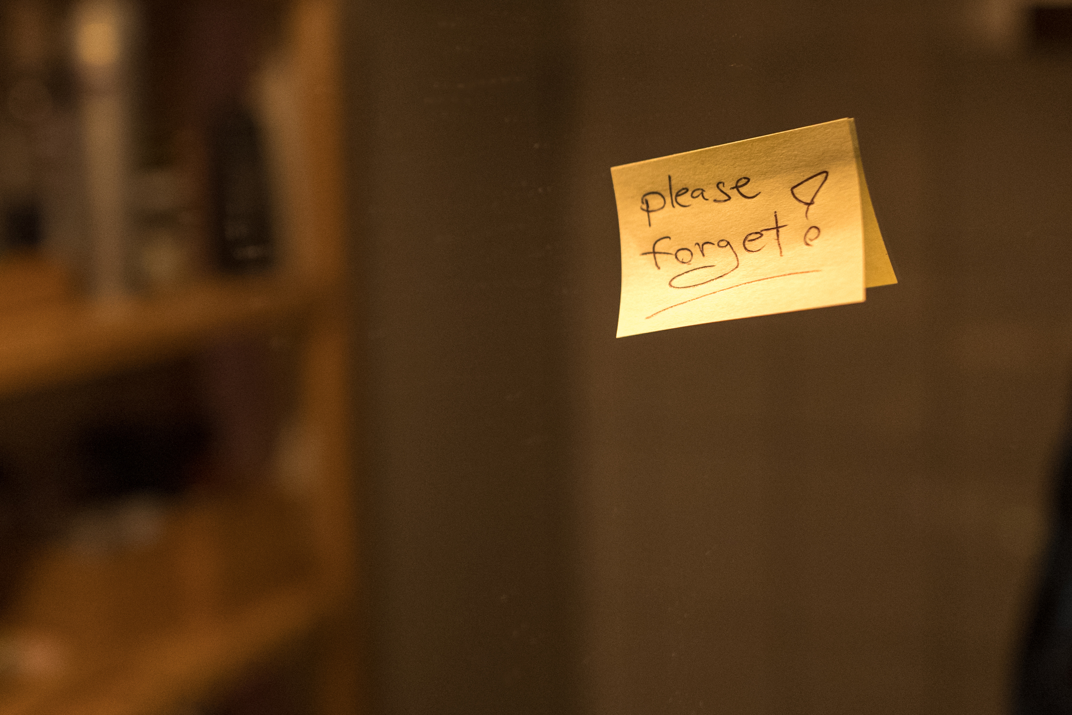 Piece of paper with inscription "Please forget" on a mirror