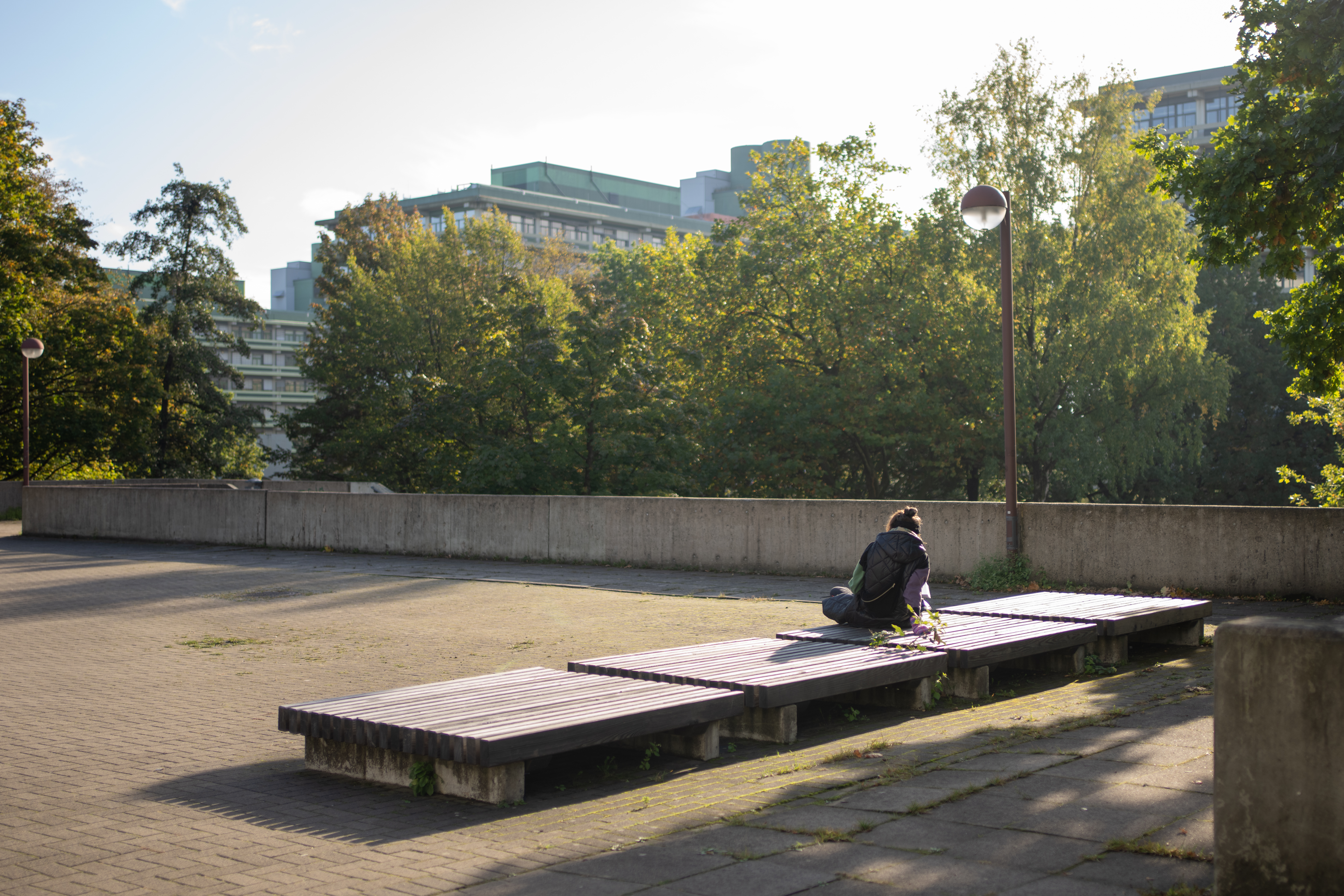 Eine Person sitzt alleine auf dem RUB-Campus.