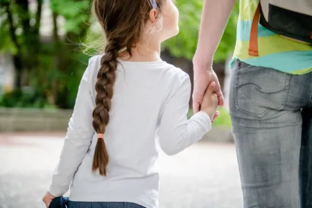 Kind von hinten, das die Hand von einem Erwachsenen hält
