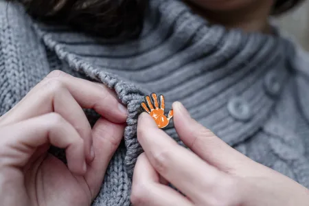 Orange-farbene Hand als Pin symbolisiert „Stopp“.