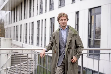 Ein Mann im Mantel lehnt an einem Geländer