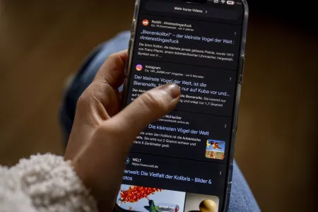 Daumen klickt auf dem Handy eine Überschrift an