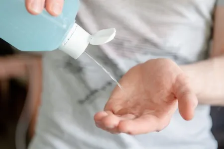 Jemand schüttet Desinfektionsmittel aus einer Flasche in seine Hand