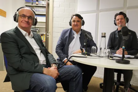 Drei Männer mit Kopfhörern in einem Studio