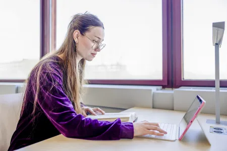 Eine junge Frau tippt in ein Laptop