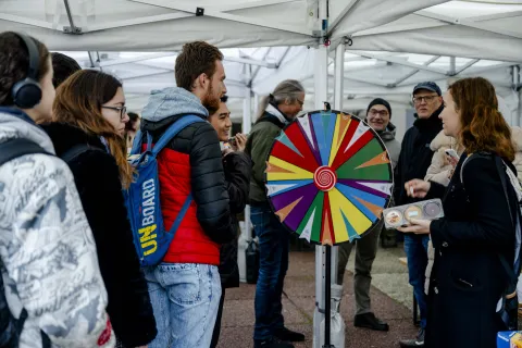 Gruppe von Leuten steht um ein buntes Glücksrad herum.