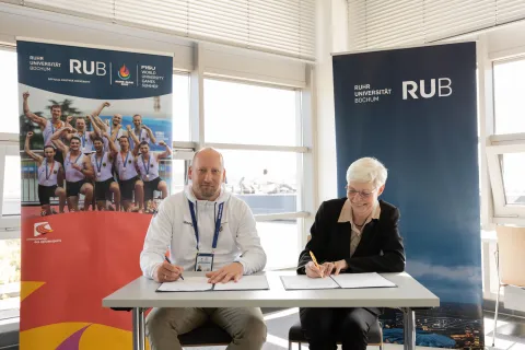 Mann und Frau sitzen am Tisch, Stifte in der Hand