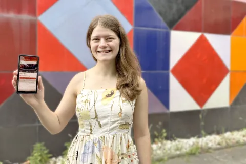 Studentin hält Handy hoch. 