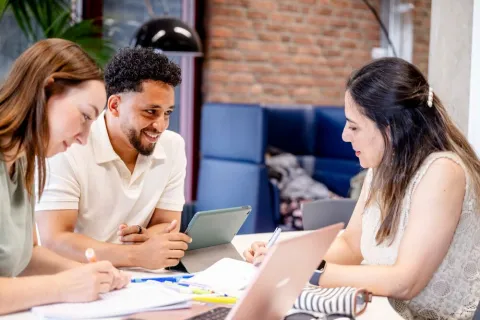 Drei Studierende sitzen in der Bibliothek