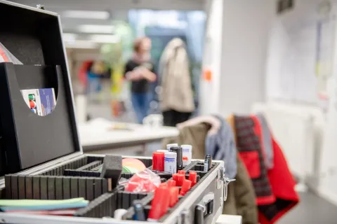 Workshop-Impression mit Moderationskoffer im Vordergrund und Personen im Hintergrund