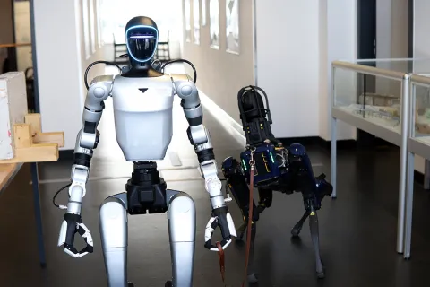 Ein humanoider Roboter hält einen hundeartigen Roboter an der Leine