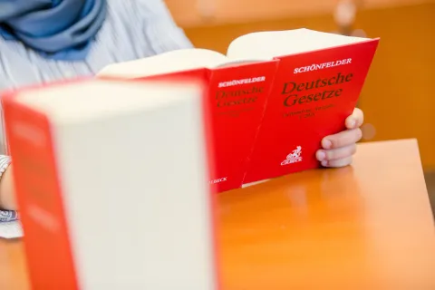 Symbolbild für die Rechtswissenschaft: Studierende hält ein rotes Gesetzesbuch in den Händen