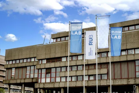 Flaggen der RUB, der TU Dortmund und des Ruhr Innovation Lab vor der Universitätsbibliothek