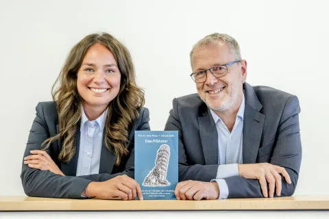 Porträt von Deborah Maffia und Stefan Winter mit dem Buch "Das PISAster"