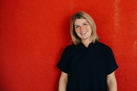 Porträt von Kristin Flugel vor einer roten Wand