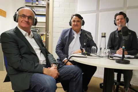 Drei Männer mit Kopfhörern in einem Studio