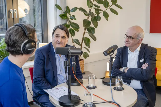 Drei Männer an einem Tisch mit Mikrofonen