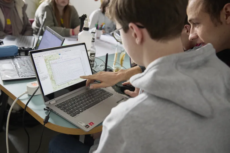 Zwei junge Männer schauen auf einen Laptopbildschirm