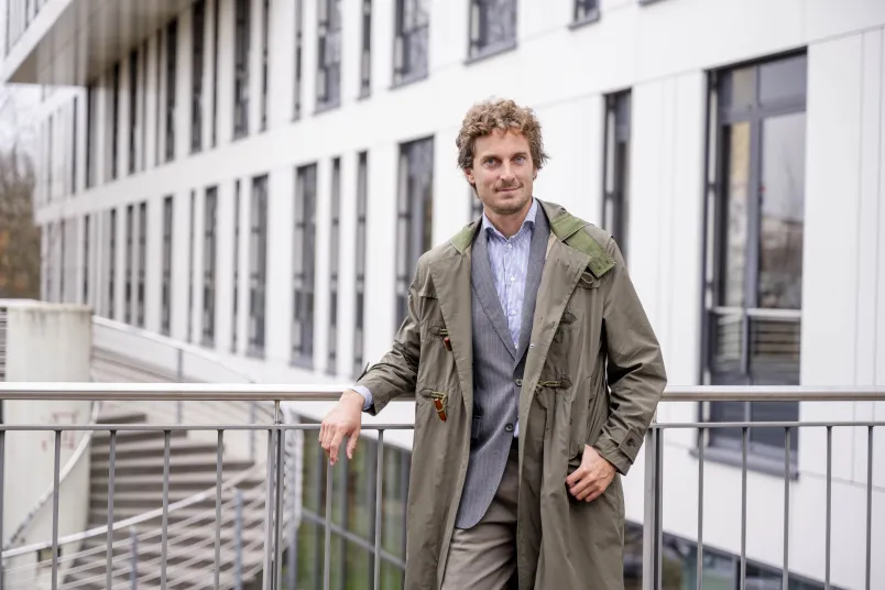 Ein Mann im Mantel lehnt an einem Geländer