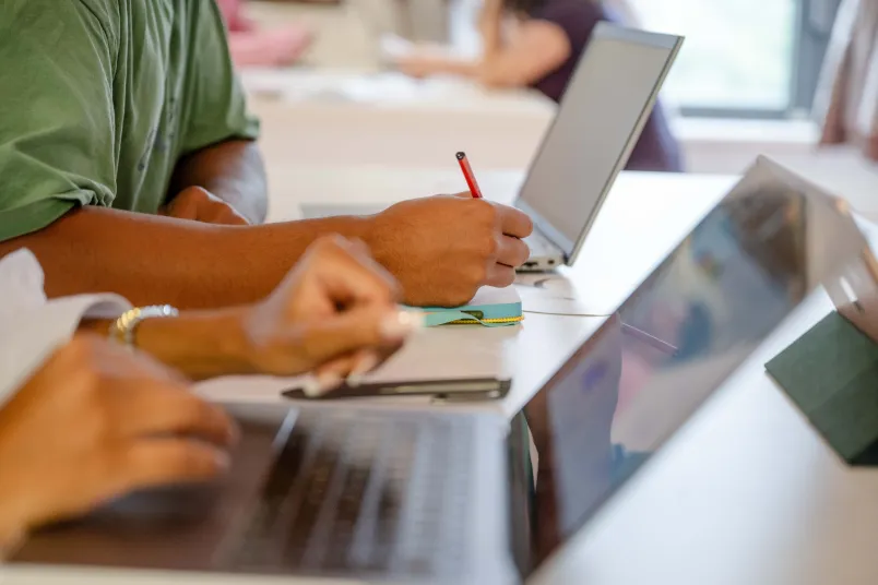 man sieht Hände und Arme und zwei aufgeklappte Laptops