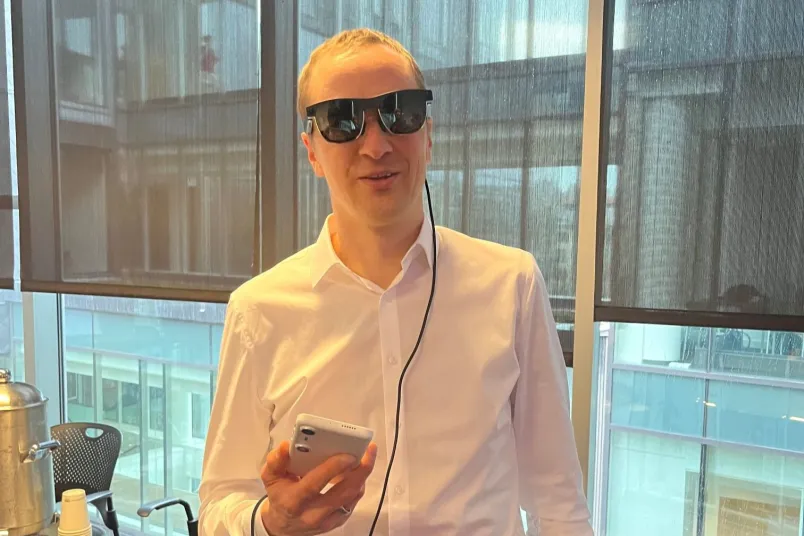 Ein Mann mit einer KI-Brille und einem Handy