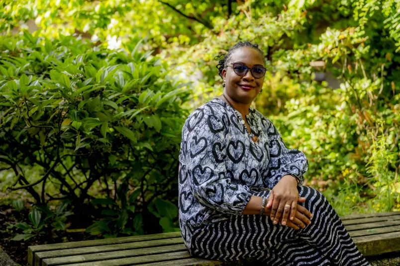 Porträt einer afrikanischen Gastwissenschaftlerin sitzend im Grünen.