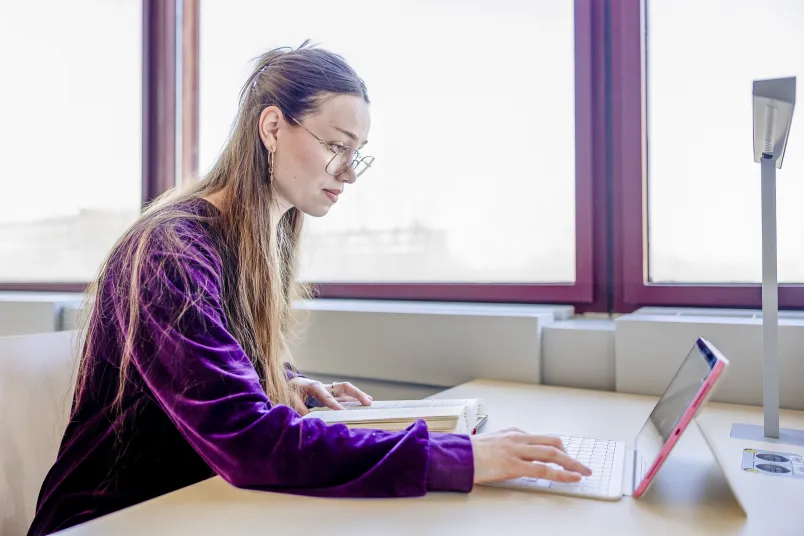 Eine junge Frau tippt in ein Laptop