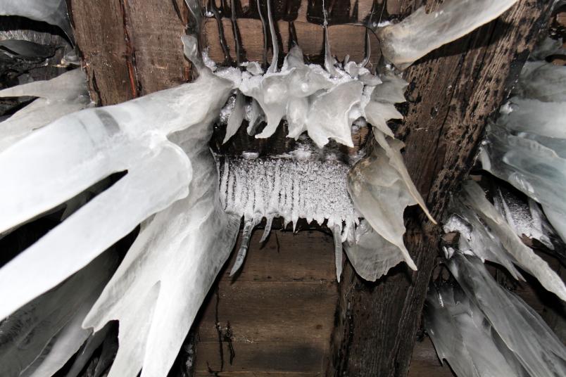 Große Eiszapfen hängen von einer Decke Richtung Kamera.