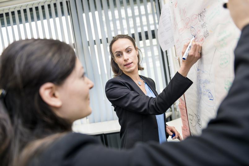 Zwei Frauen stehen an einer Flipchart und schreiben darauf.