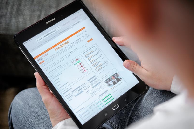 Ein Mann liest das Handelsblatt auf einem mobilen Gerät.
