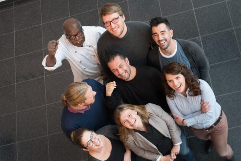 Eine Gruppe von lachenden Menschen von oben fotografiert.