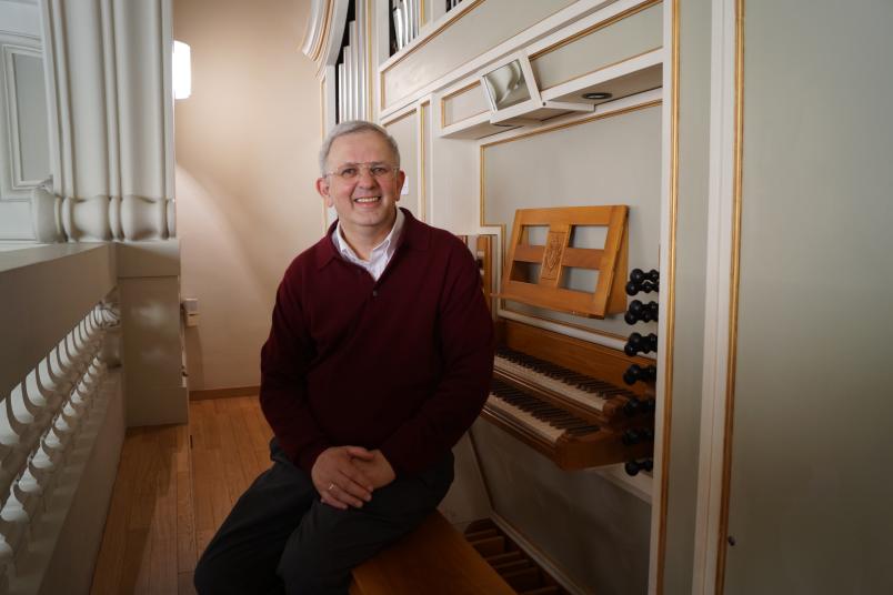 Porträt eines etwa 60-jährigen Mannes, der vor einer Orgel sitzt
