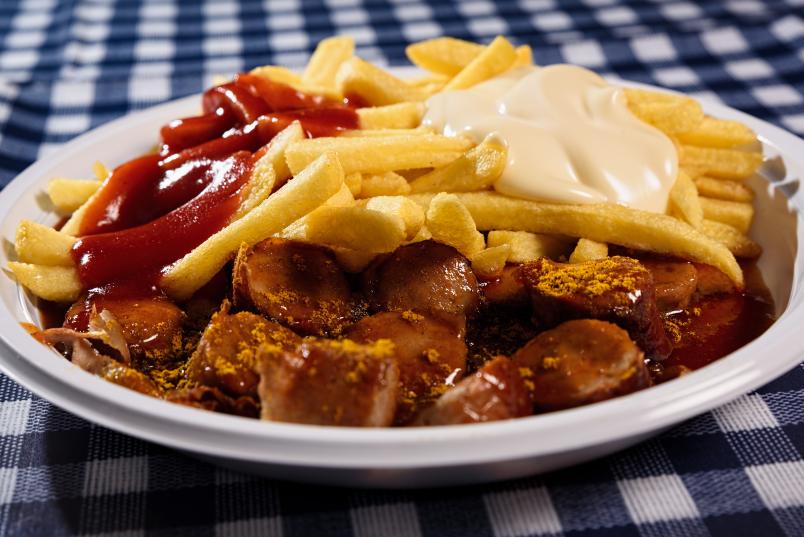 Teller mit Currywurst und Pommes frites