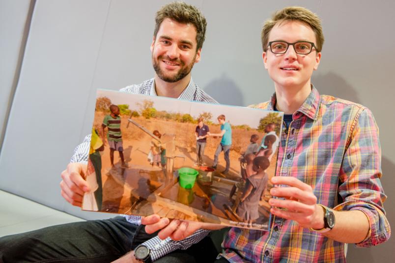 Zwei Männer halten im Sitzen ein Bilderbuch.