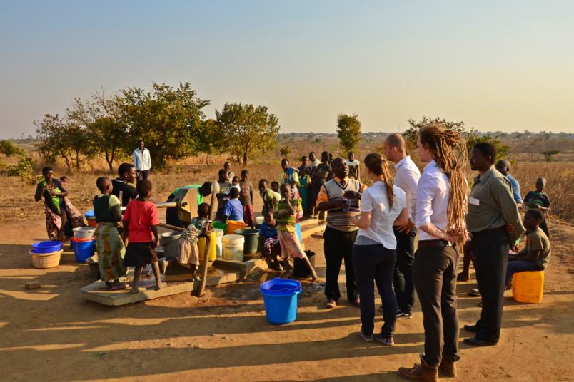 Viele Kinder und wenige Erwachsene versammeln sich an einer Pumpe in einem malawischen Dorf.