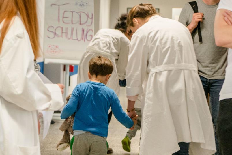 Viele Menschen im weißen Kittel und ein Kind von hinten